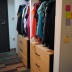 The photo shows two closets both with dressers in the bottom of them under hanging clothes.